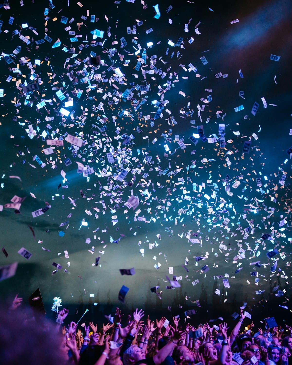 Crowd at a Happening Co. event, hands raised under warm stage light